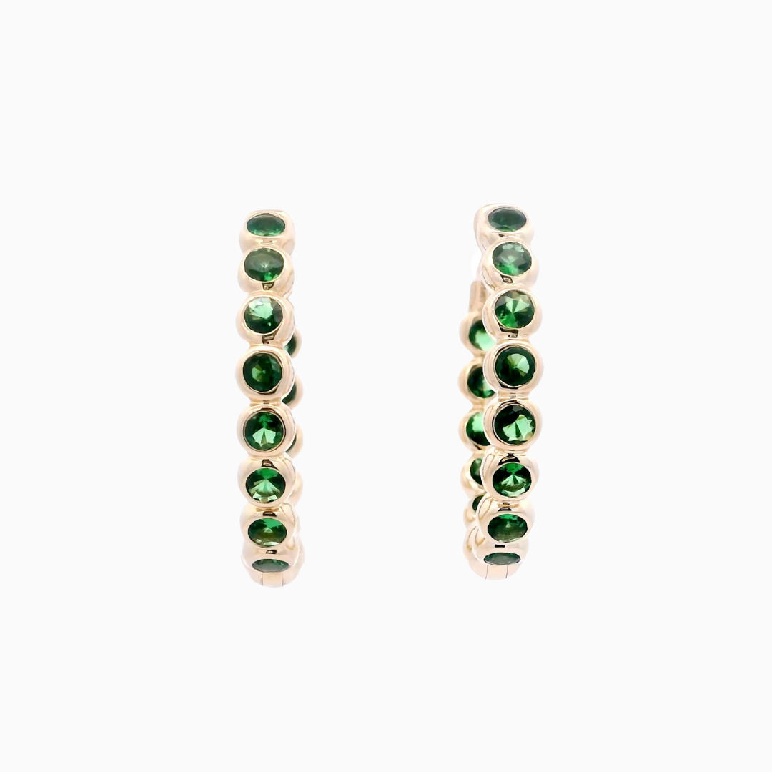 Pair of gold earrings with green gemstones on a white background