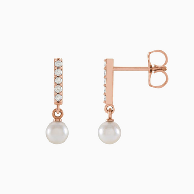 Constructed from 14k gold, these diamond bar earrings boast a cultured akoya pearl drop and .03 CTW of natural diamond  Choose from yellow, white, and rose gold.