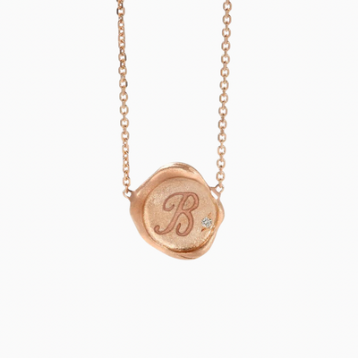 A custom engraved necklace resembling a wax stamp with solitary diamond in our handmade setting.   'Please add order note for the requested letter to engrave'   solid 14k gold 10 mm charm 0.01 tcw diamond matte sparkle finish