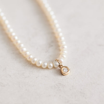 16-17" baby white button freshwater pearsl and a CTW natural diamond pendant set in 14k yellow gold, finished with a 14kt gold magnetic clasp. Handmade by Nicole Gerulat.