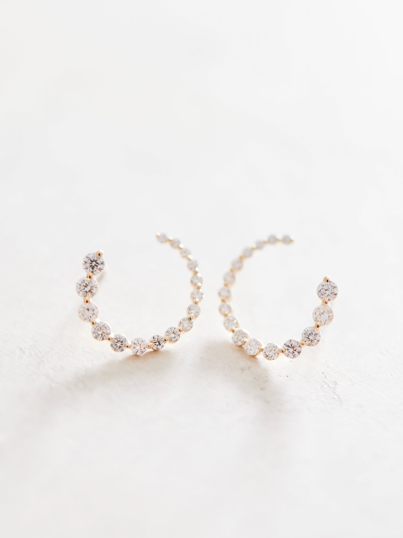 These front-back diamond earrings have 7/8 ctw natural diamonds set in 14k gold. The graduated end tucks behind the lobe for a beautiful illusion of a completed circle that stays facing front. 15mm. Available in white, yellow and rose gold.